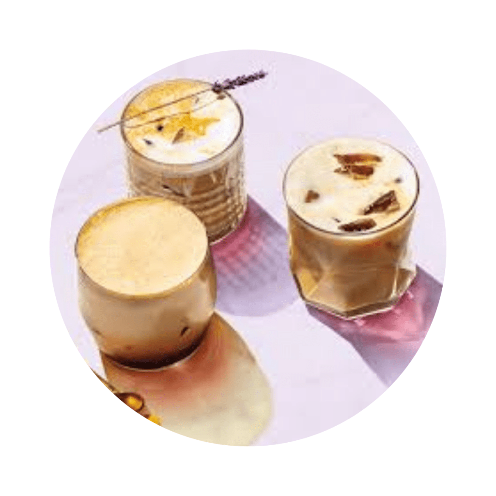 A cluster of three lavender Lattes in glass cups, two are iced, one is hot. A sprig of fresh lavender rests across the top of one of them.